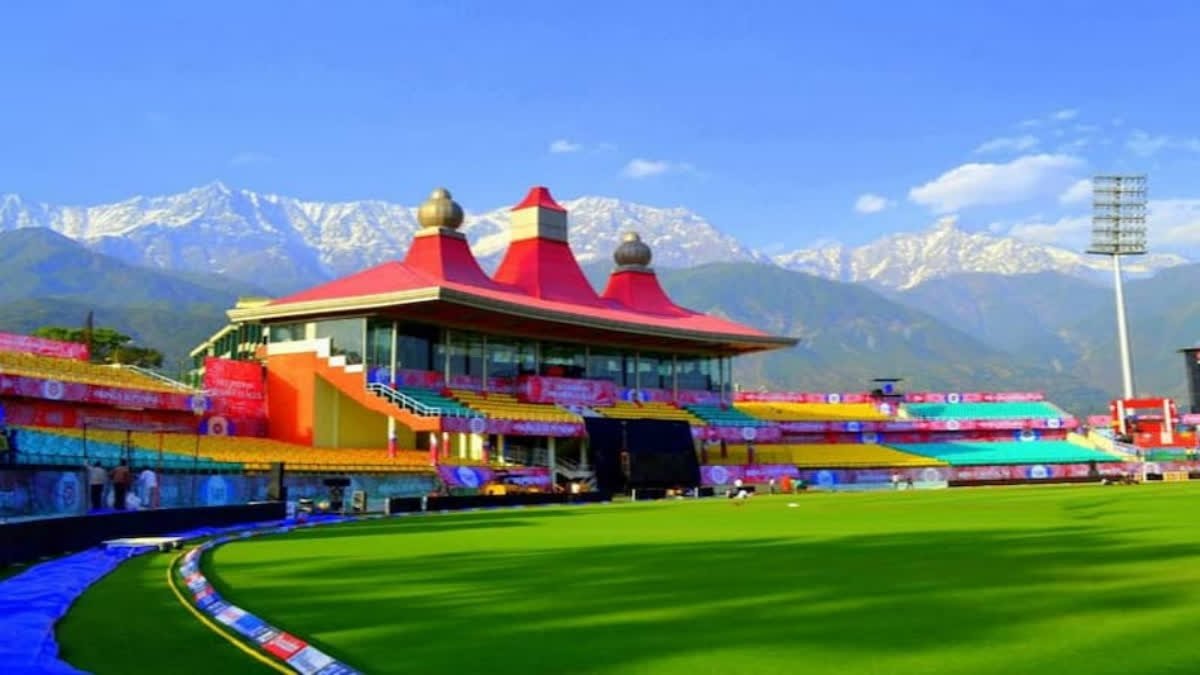 An aerial view of a cricket stadium nestled amidst picturesque mountains.